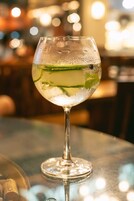 A glass of cocktail with lime and mint on a bar counter.