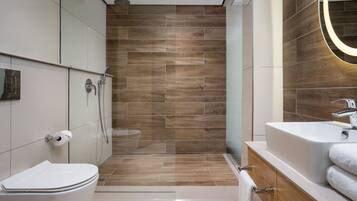 Een moderne badkamer met toilet, douche en wastafel.