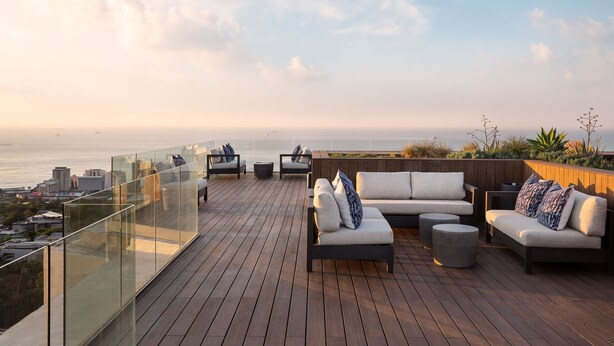 A rooftop terrace with outdoor seating, a glass balustrade, and a view of the city and sea. - Premier Splendid Inn Umhlanga (Umhlanga)
