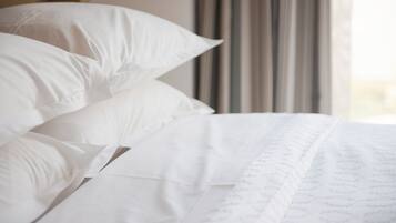 A neatly made bed with white linens and a subtle pattern.