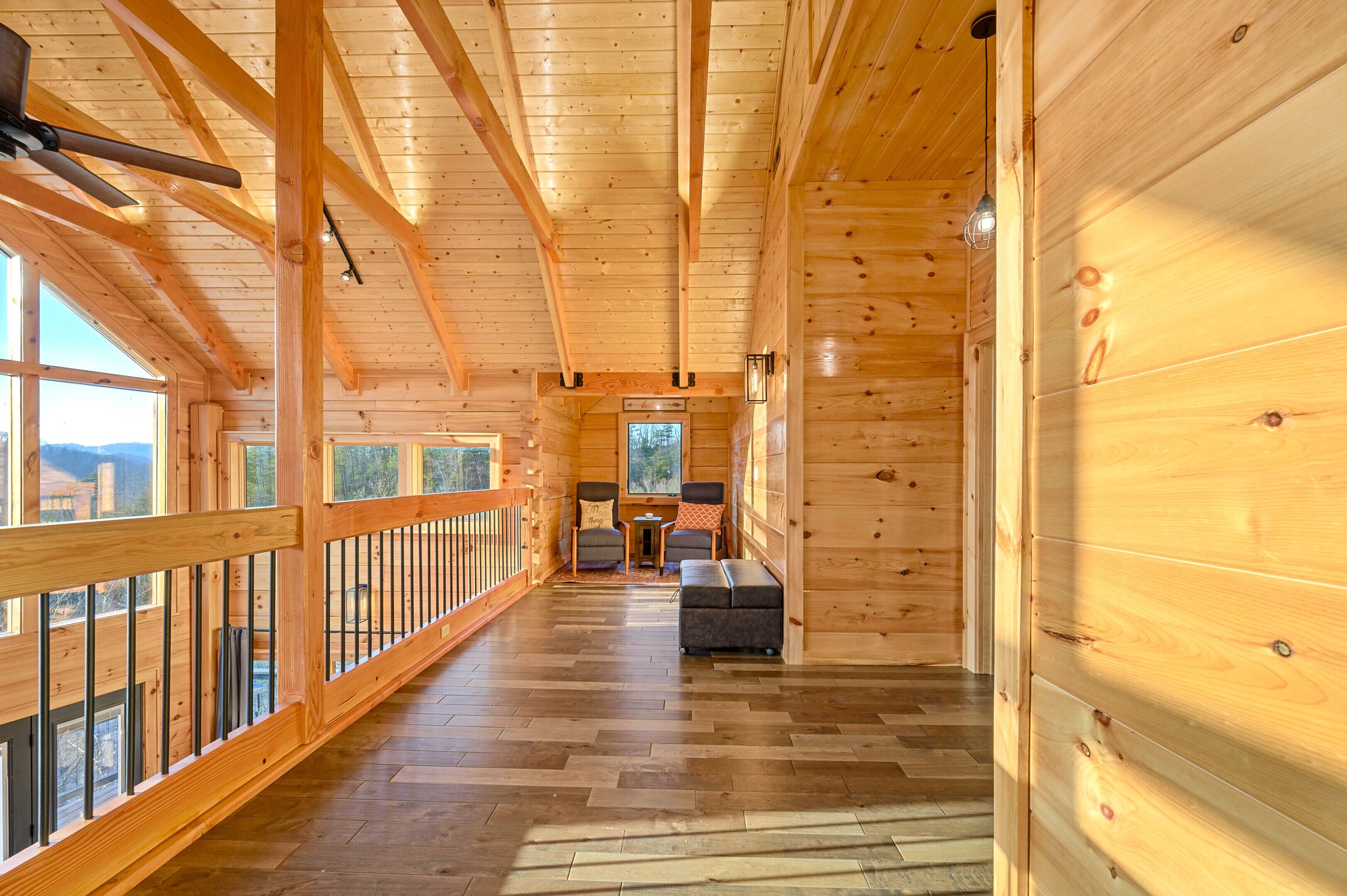 A wooden cabin interior with a long hallway, wooden floors, and large windows.