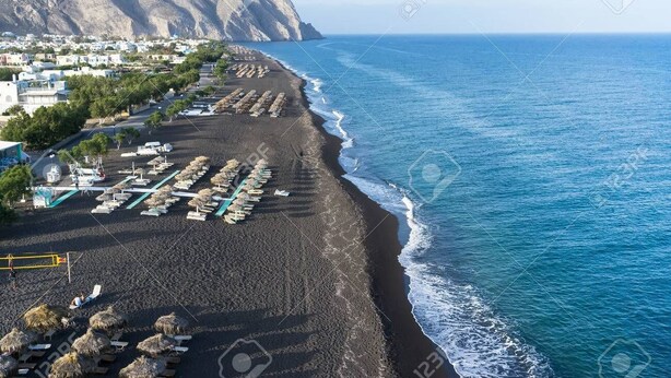 Une zone côtière comprenant une plage, une montagne et une rangée de bâtiments.