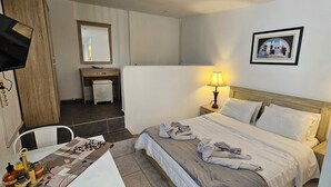 Ein Hotelzimmer mit Bett, Nachttisch, Lampe und Schreibtisch mit Stuhl.