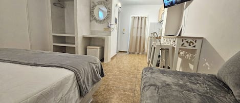 A hotel room with two beds, a TV mounted on the wall, a mirror, and a small seating area.