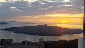 A sunset over a calm sea with a ship in the foreground and distant islands. - Room in Studio - Pleasure Room 4 By The Sea (Santorini)