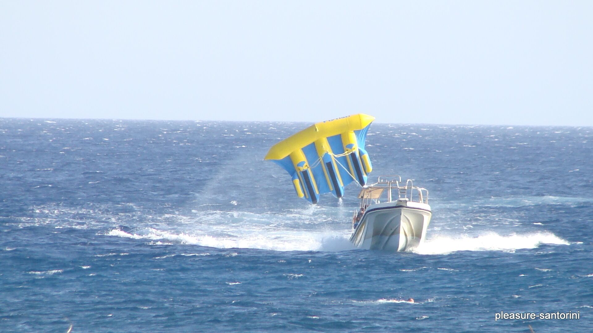 A boat with a yellow and blue parasail in the ocean.