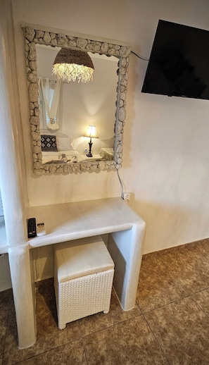 Bathroom features a vanity with a mirror and a television mounted above.