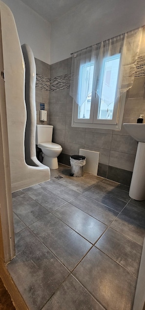 Bathroom features a toilet, bidet, and sink, with a window for natural light.
