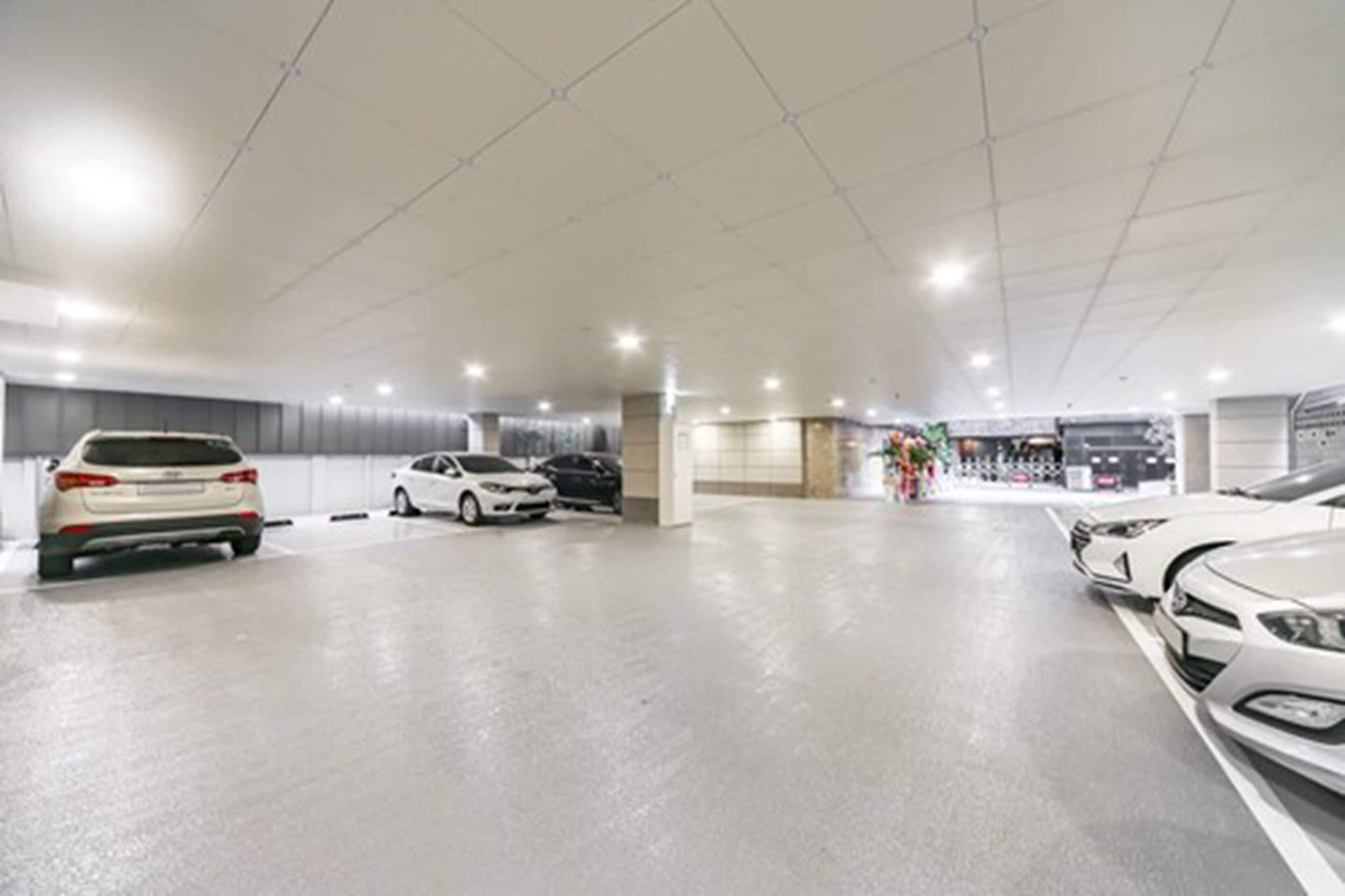 A spacious indoor parking area with multiple cars parked.