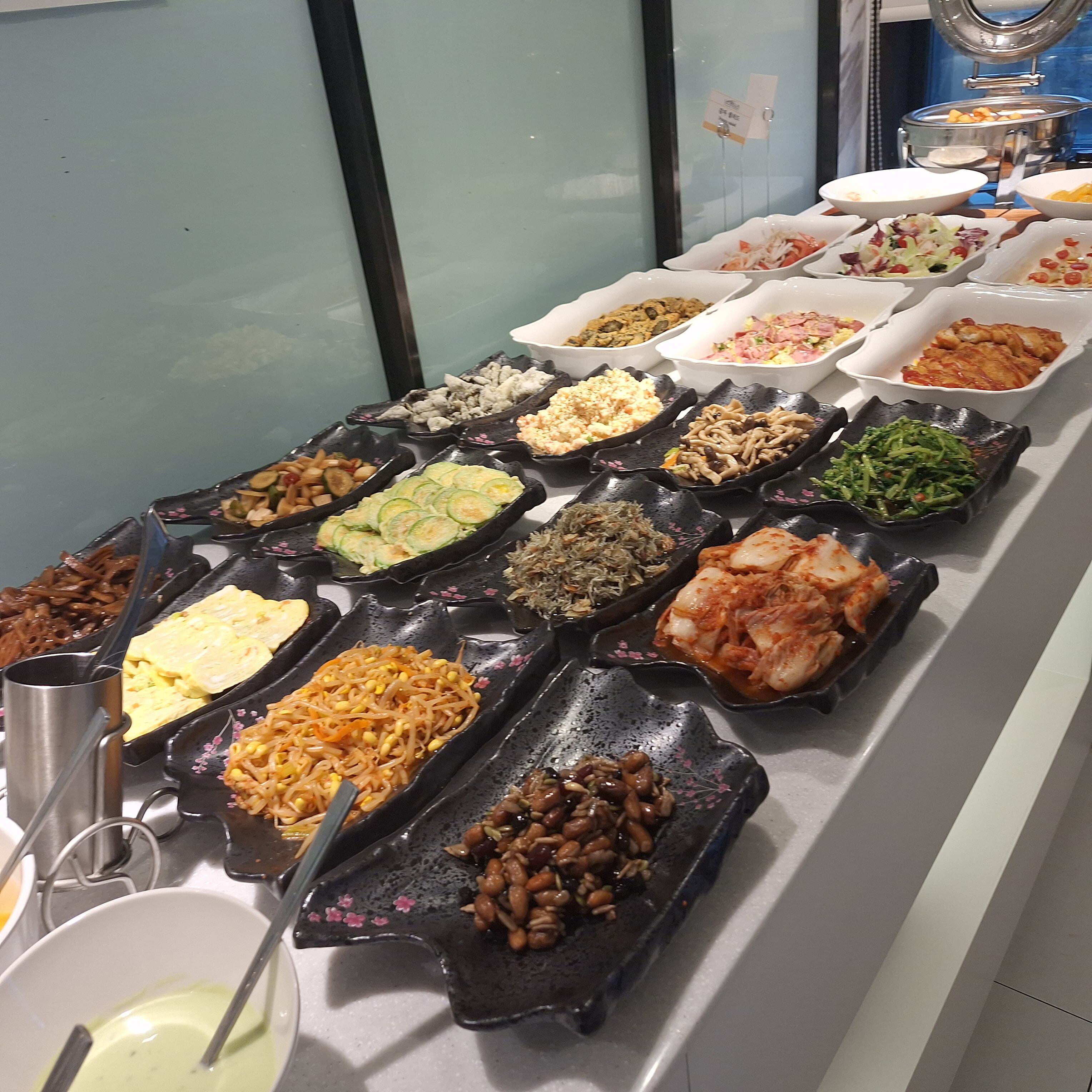 A buffet with various dishes arranged in black and white bowls.