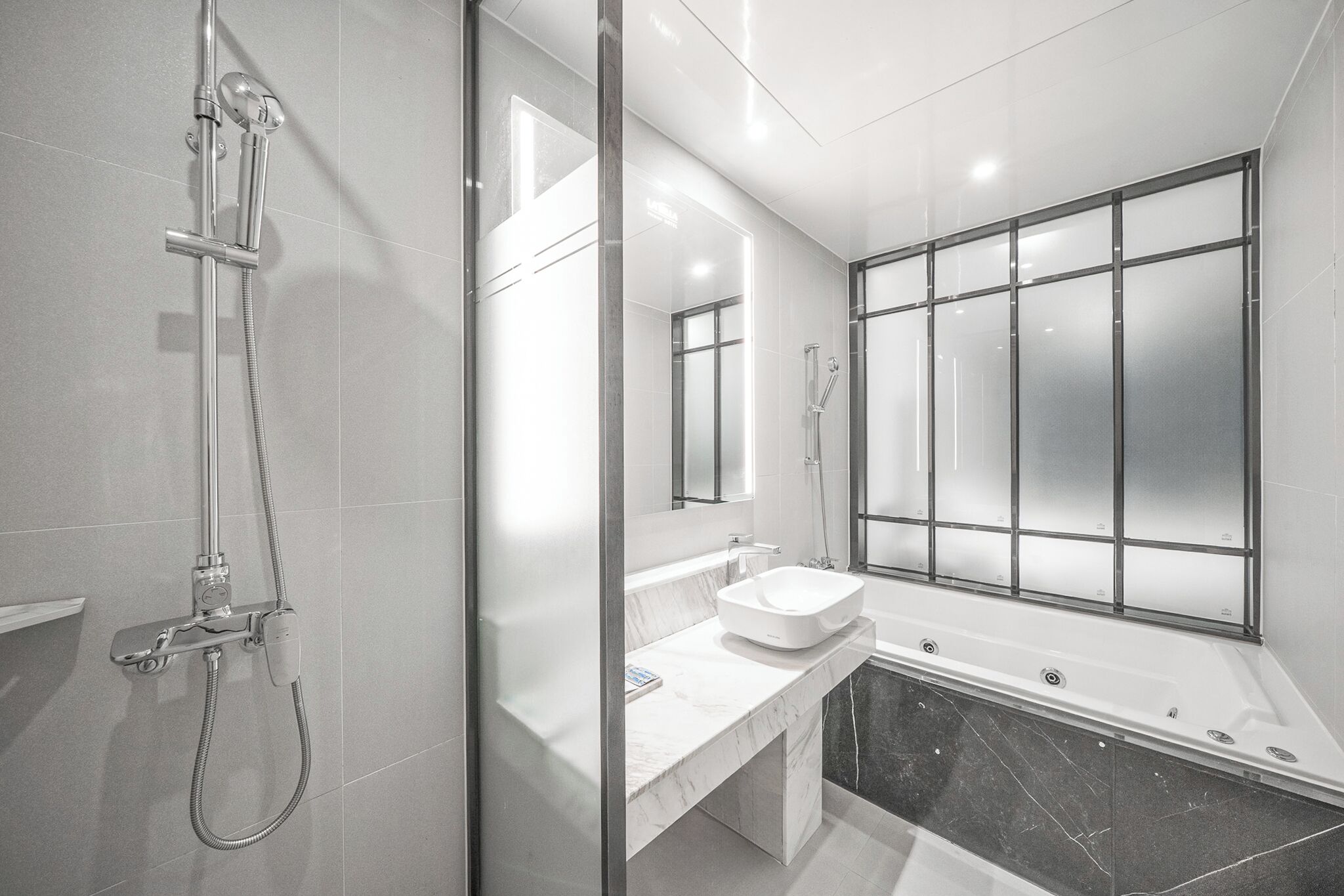 A modern bathroom with a glass-enclosed shower, a white sink, and a large bathtub.