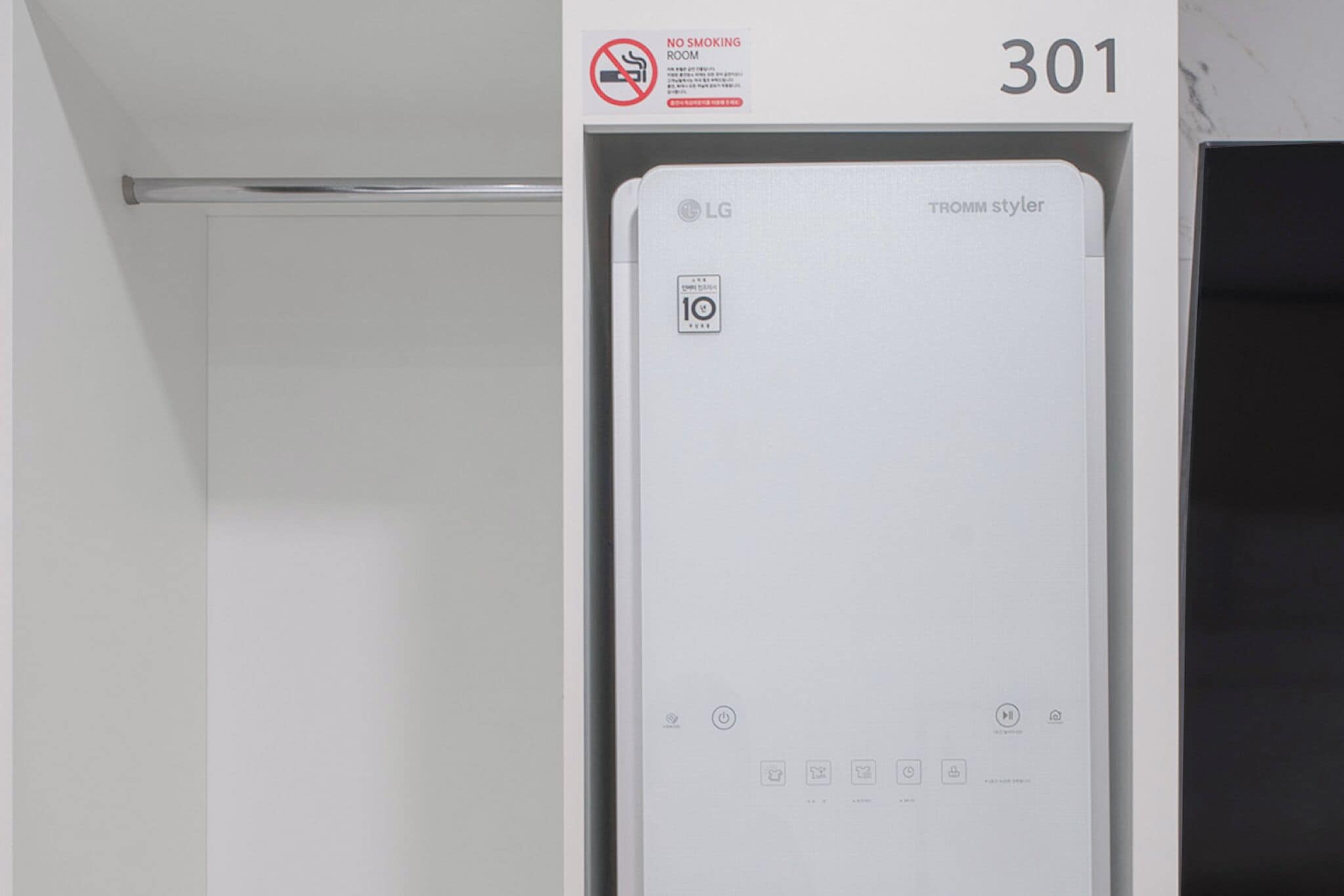 A white LG TROMM styler water heater in a room with a 'No Smoking' sign and the number 301 on the wall.