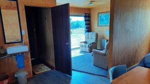 A room with a wooden interior, a sink, a chair, a table, and a view of the outdoors. - Stargazer's Cabin (Saint Arnaud)