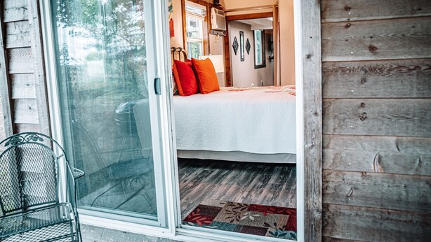 Ein gemütliches Schlafzimmer mit einem Bett, einem Fenster und einer Tür zu einem weiteren Raum.