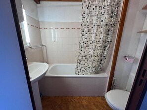 Un baño con bañera, inodoro y cortina de ducha.