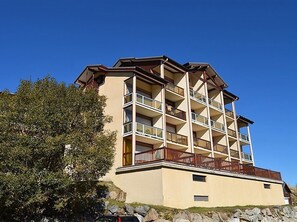 Un edificio de varios pisos con balcones, techo plano y base de piedra.