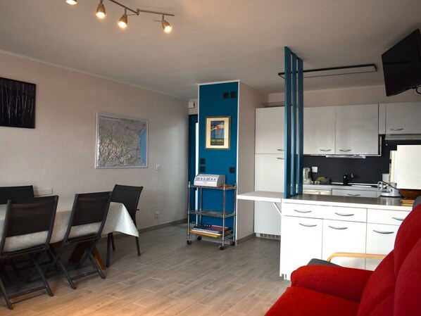 Un salon moderne comprenant un coin repas, une cuisine et un mur d’accent bleu.
