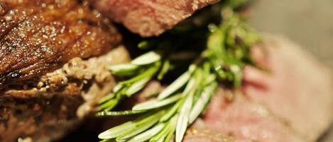 Une vue rapprochée d’un plat de viande cuit, dont une tranche a été coupée, et qui est décoré de romarin.