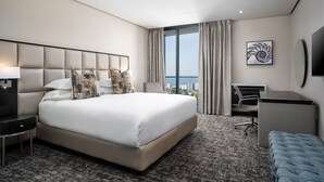 Une chambre d’hôtel moderne avec un grand lit, un bureau, une chaise et une vue sur la ville.