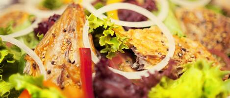 Primer plano de una ensalada con diversas verduras y un trozo de pescado a la parrilla.