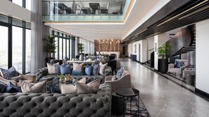 Un hall d’entrée spacieux avec un plafond haut, un mobilier moderne et un escalier.