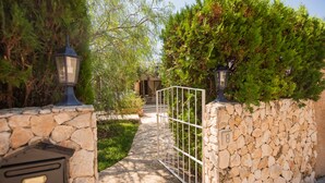 A stone wall with a metal gate, a mailbox, and a pathway leading to a building. - Beach House Villa Isabel (Santanyí)