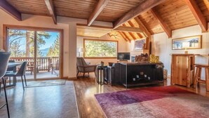 A spacious living area with a wooden ceiling, a fireplace, a television, and a view of the outdoors. - Lakeview Serenity Cottage (Kings Beach)