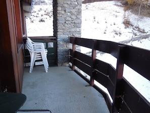 A covered outdoor seating area with a stone wall and a wooden railing.
