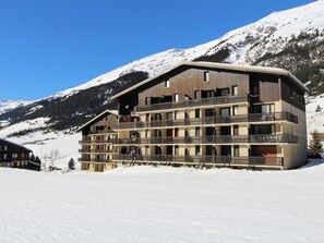 Ein mehrstöckiges Hotel mit Balkonen vor verschneiten Bergen.