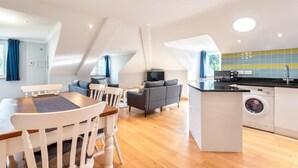 A modern apartment with a dining area, living room, kitchen, and a washing machine. - Spacious Flat A Few Mins Walk to Carlyon Bay Beach (Carlyon Bay)