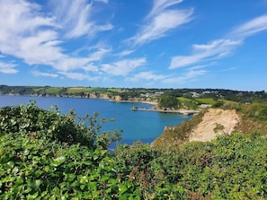 Paisatge costaner amb una vista clara del mar, una platja sorrenca i una població a la distància.
