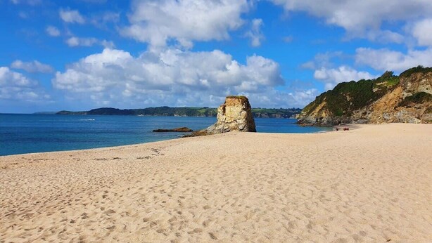 A sandy beach with a rocky outcrop in the center, a clear blue sky, and calm sea. - Spacious Flat A Few Mins Walk to Carlyon Bay Beach (Carlyon Bay)