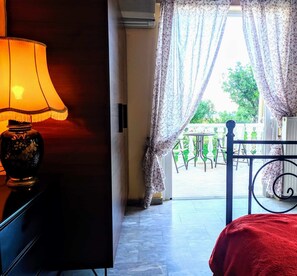 Relax in this serene retreat with a comfortable bed and a balcony offering a view of lush greenery.
