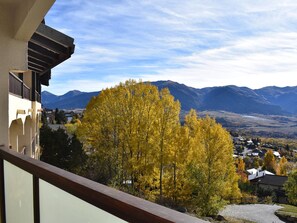 Uma varanda com vista para árvores amarelas de outono e montanhas ao longe.