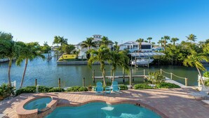 Un hôtel situé au bord de l’eau, doté d’une piscine, de palmiers et de bateaux.
