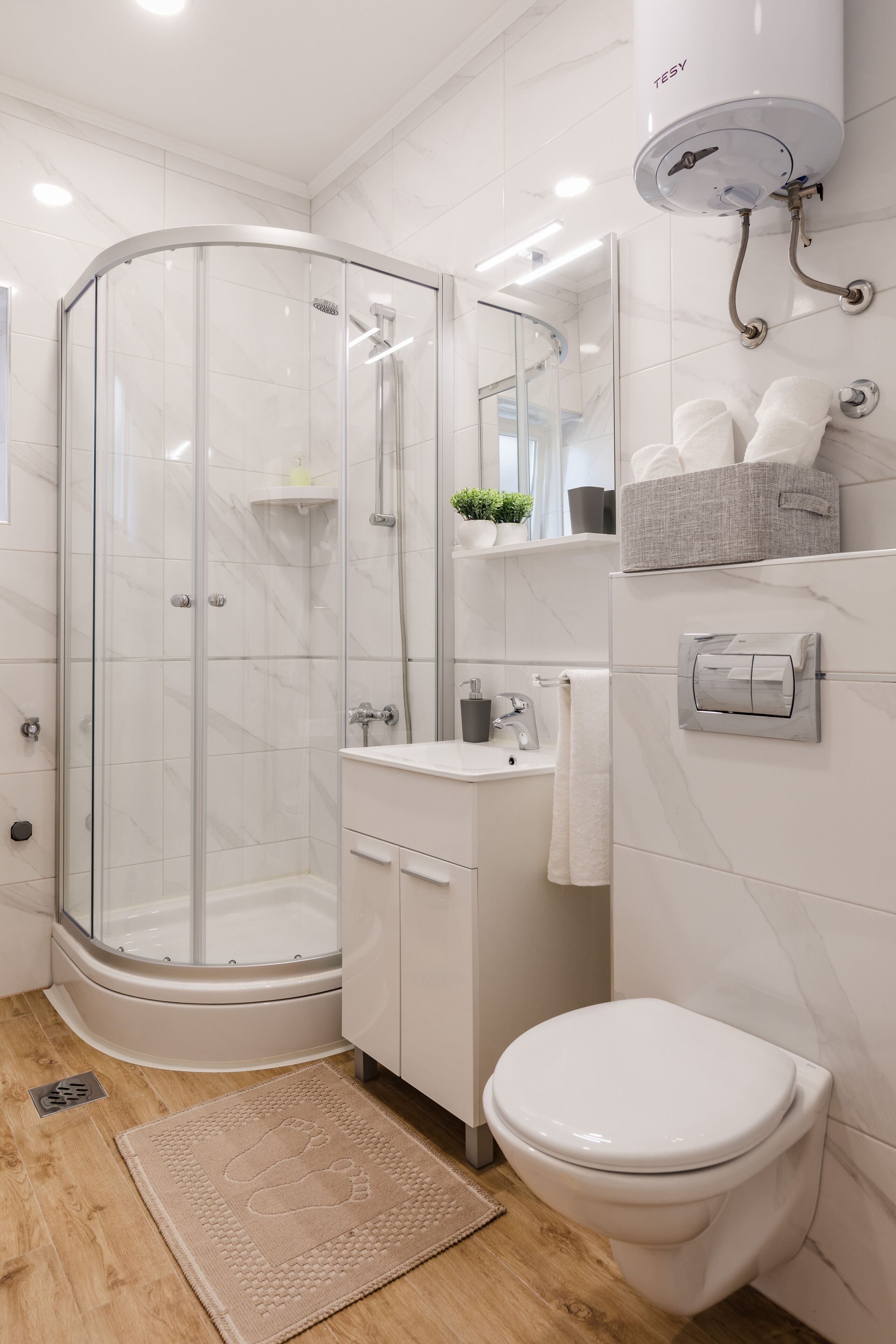 Ein modernes Badezimmer mit einer Duschkabine, einem weißen Waschbecken und einer Toilette.