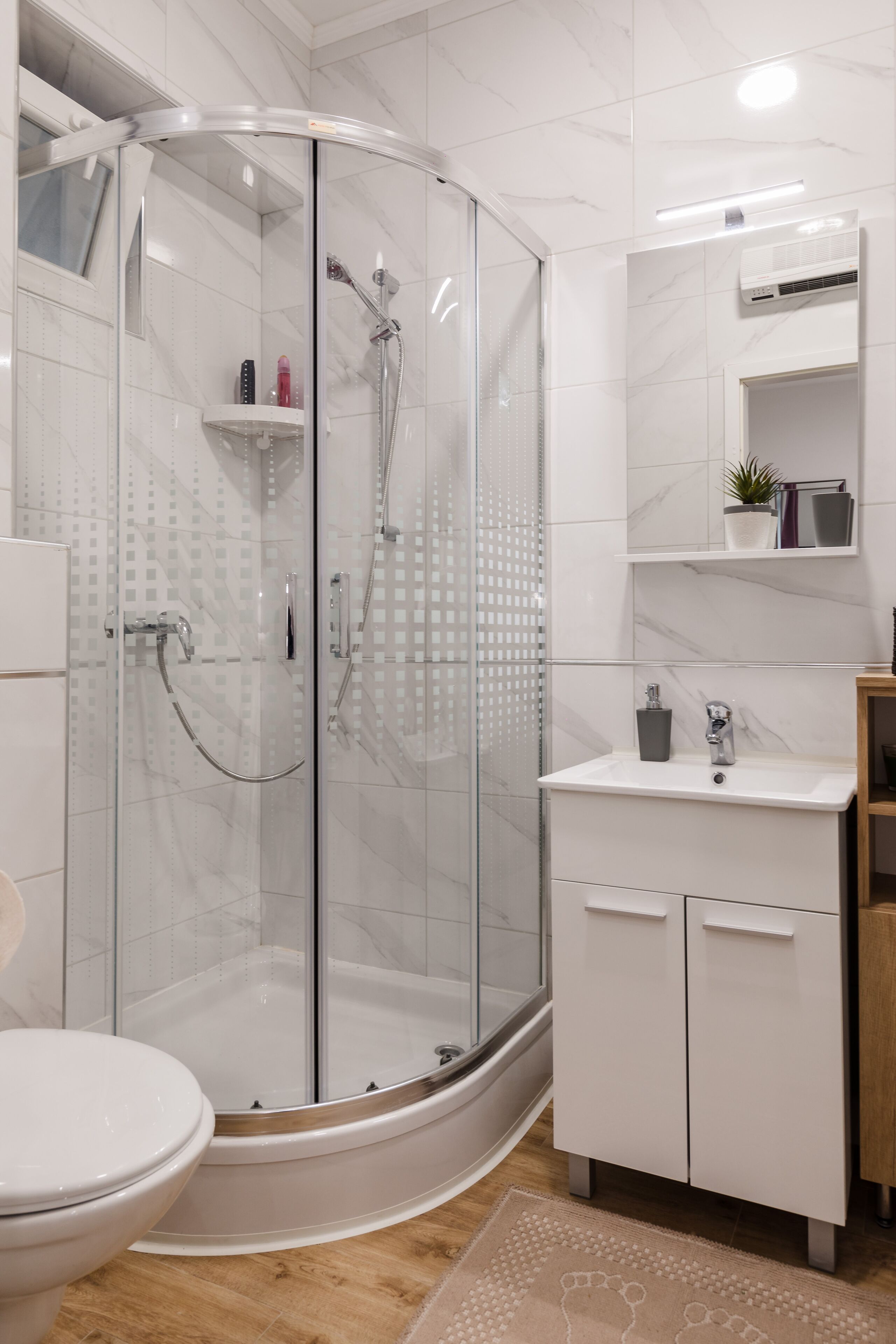 A modern bathroom with a glass-enclosed shower, a white sink, and a toilet.