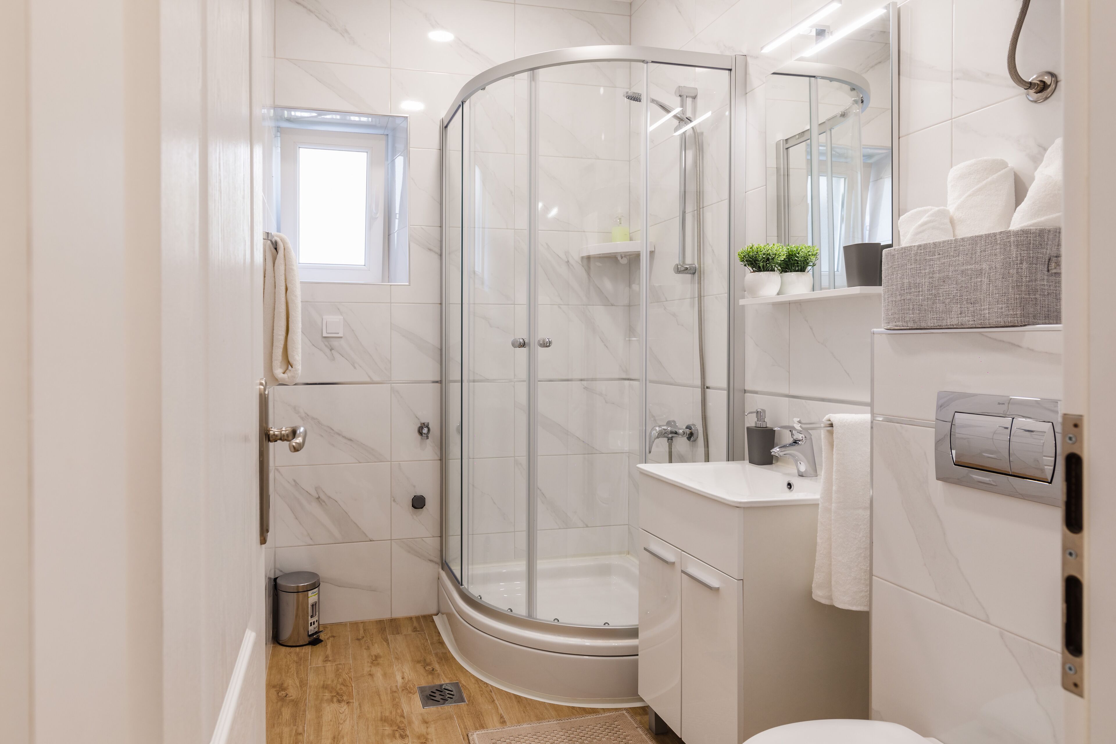 Ein modernes Badezimmer mit einer Duschkabine, einer Badewanne und einem Waschbecken mit Spiegel.