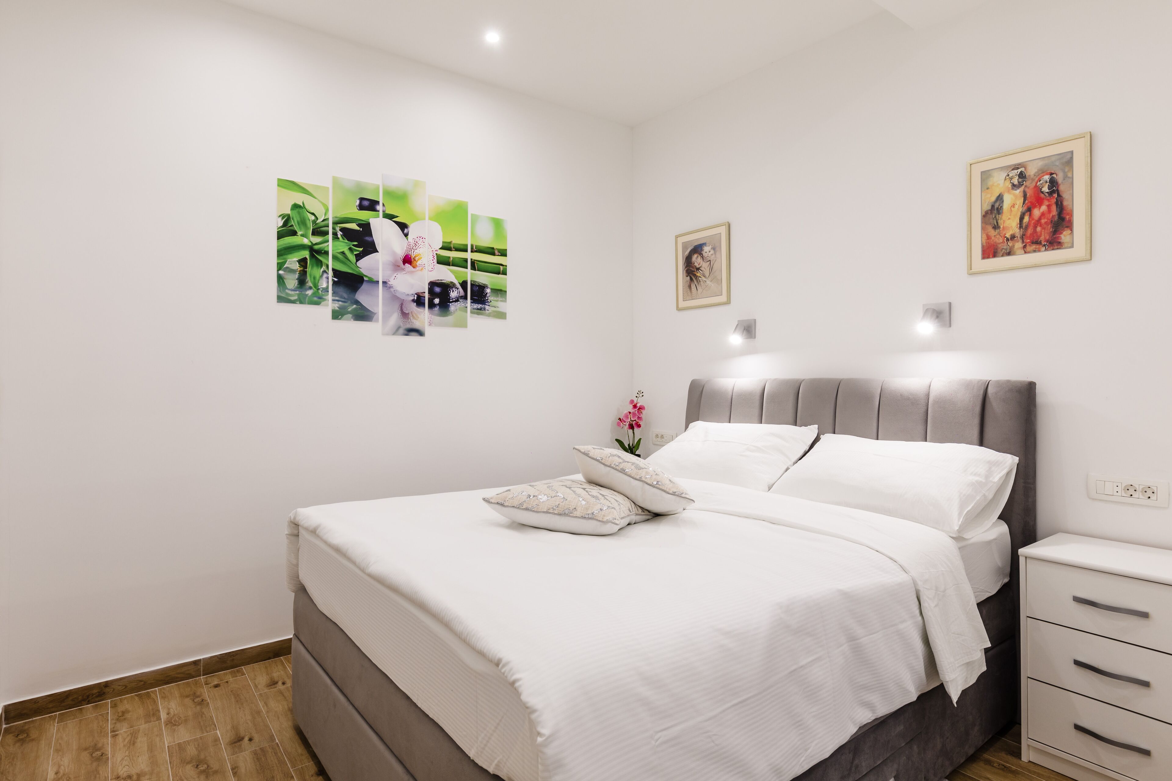 A bedroom with a bed, a nightstand, and wall art.