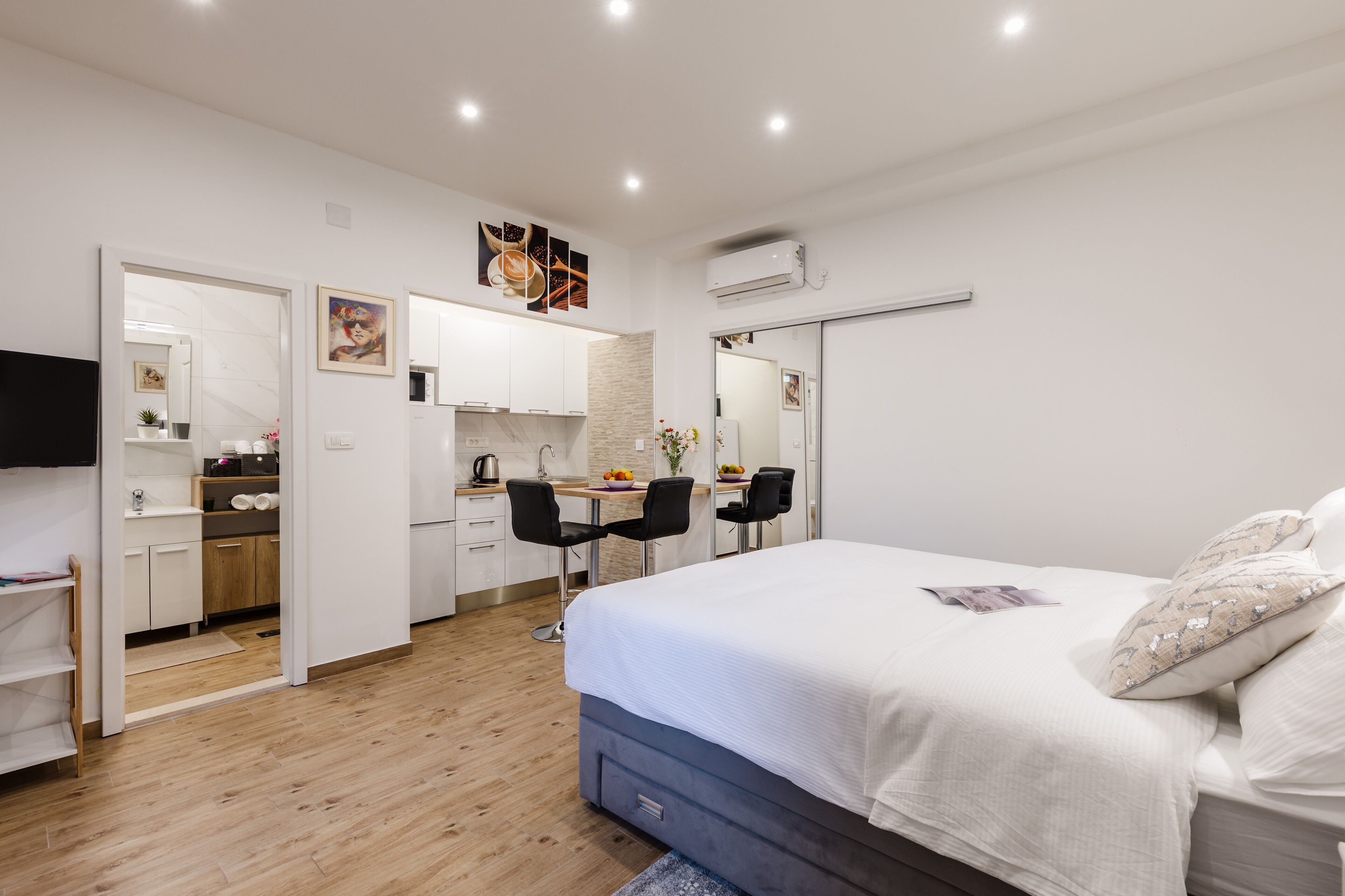 Une chambre moderne avec un grand lit, un bureau avec deux chaises et un coin cuisine.