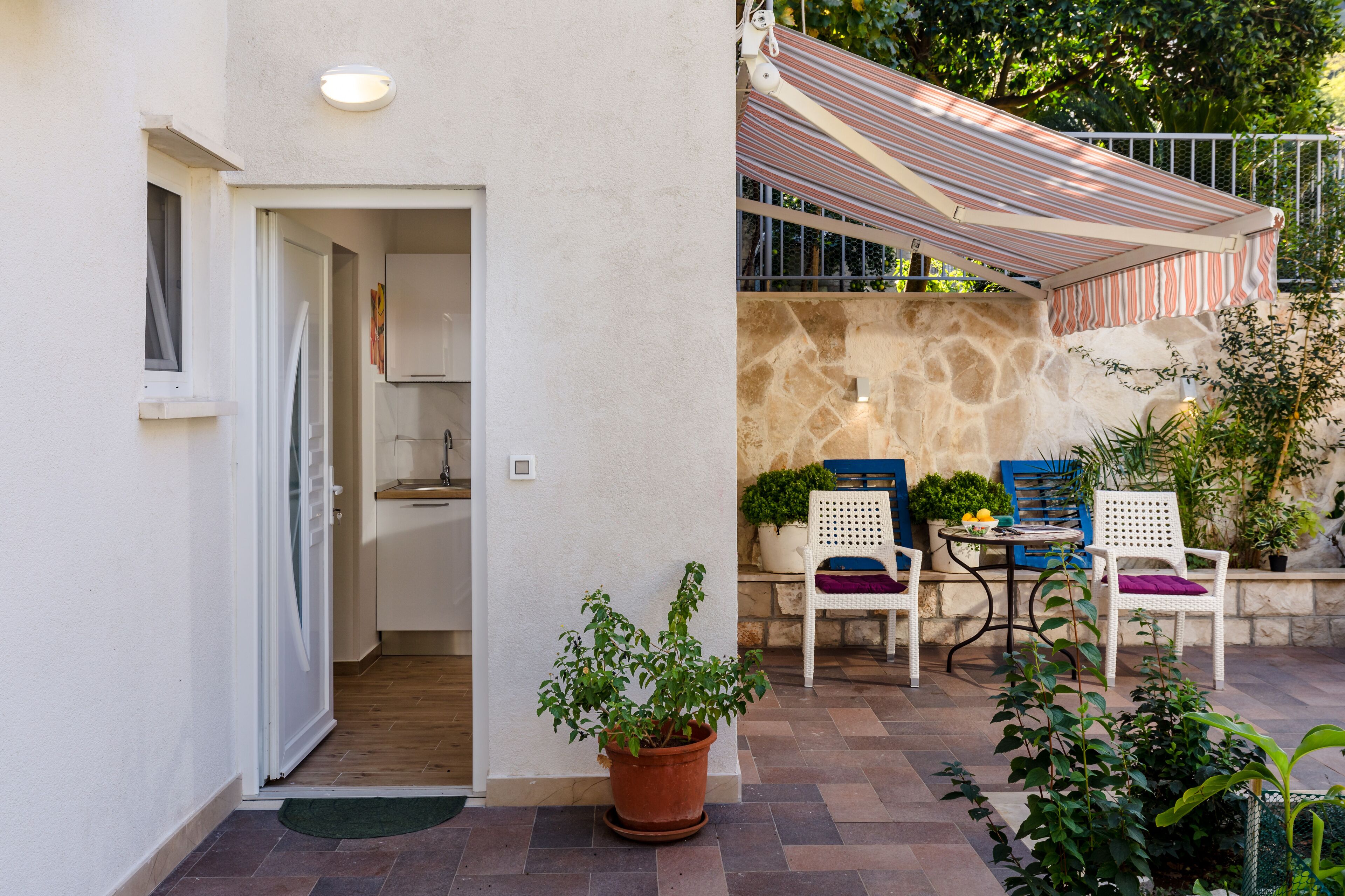 A patio area with a stone wall, a striped awning, and outdoor seating.