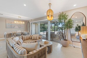 A modern living room with a sofa set, a dining area, and a large potted plant.