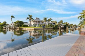 A waterfront property with a dock, a house with a balcony, and palm trees.