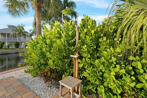 A patio area with a small table, a water feature, and lush greenery.