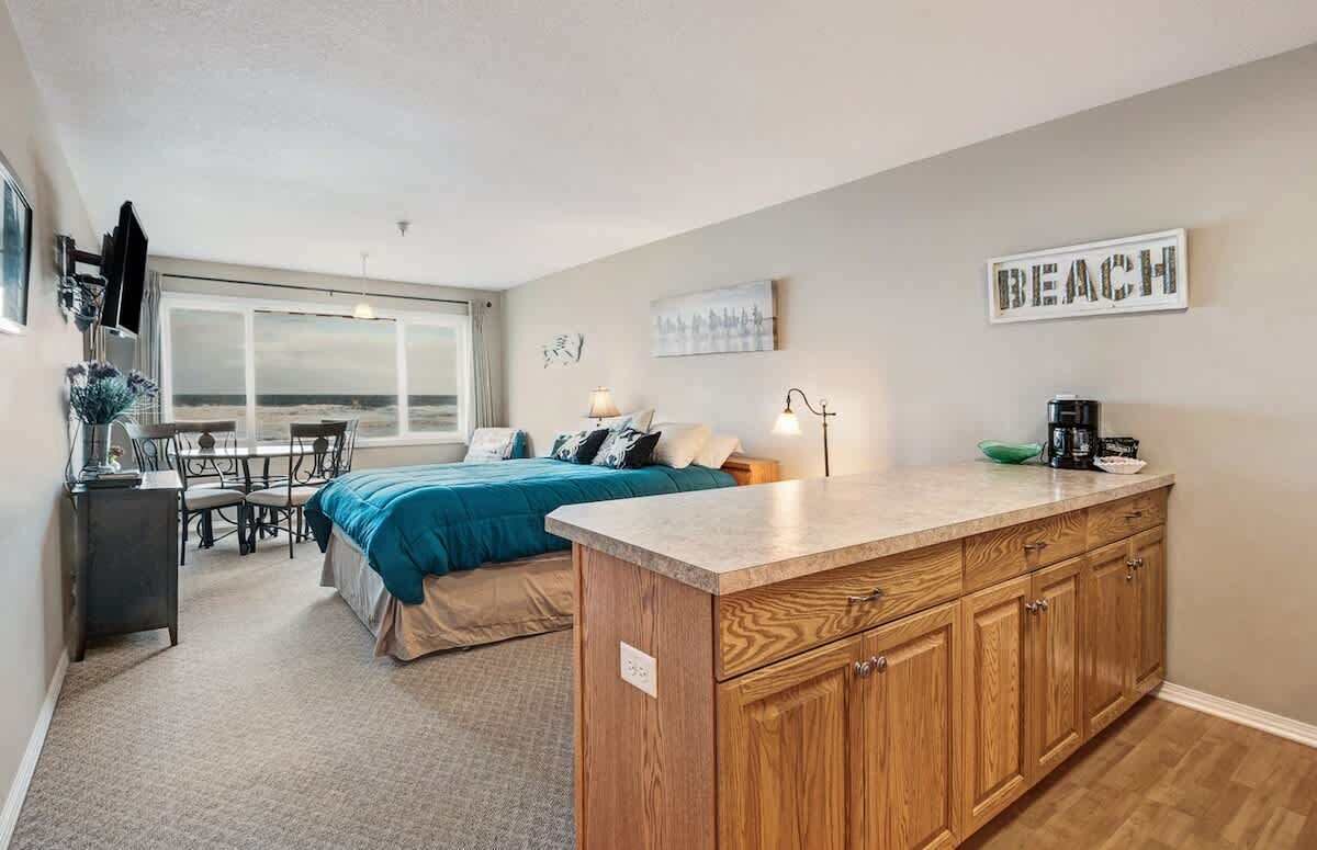 A bedroom with a large bed, a desk, and a view of the beach.