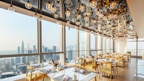 Un restaurante en un edificio alto con vistas a la ciudad, decoración moderna y abundante espacio para sentarse.