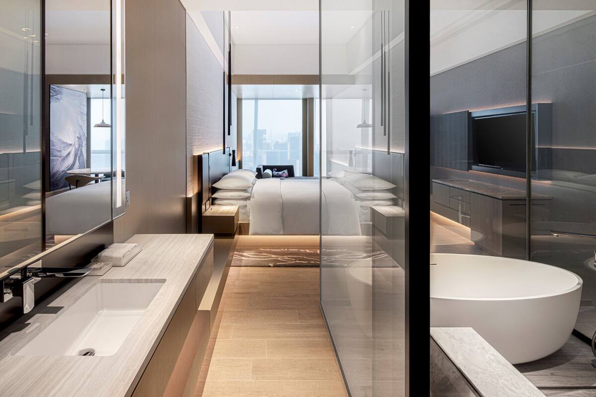 A modern hotel bathroom with a large bathtub, a separate shower area, and a vanity with a sink.