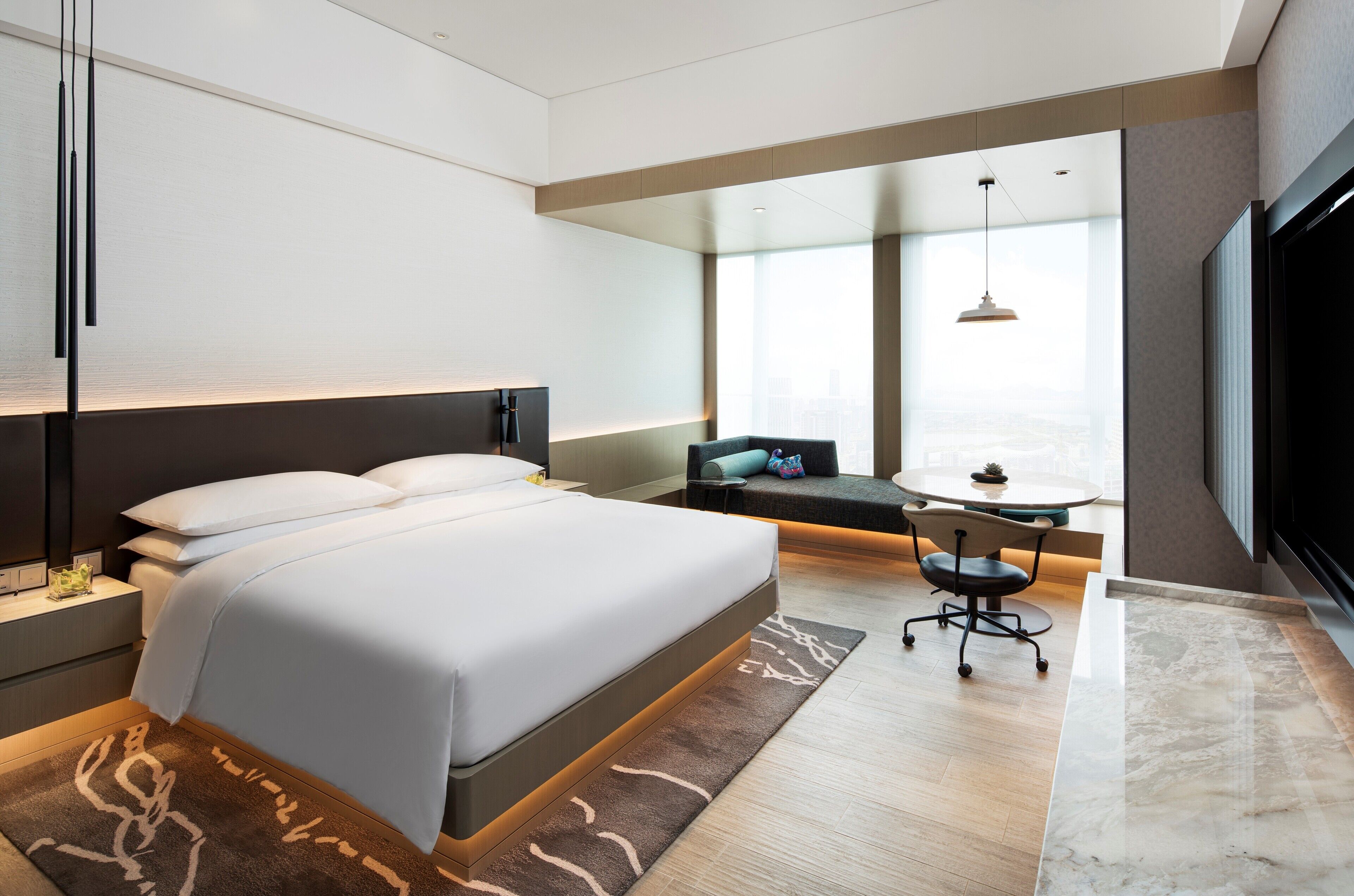 Camera d'albergo moderna con un ampio letto, una scrivania e vista sulla città.