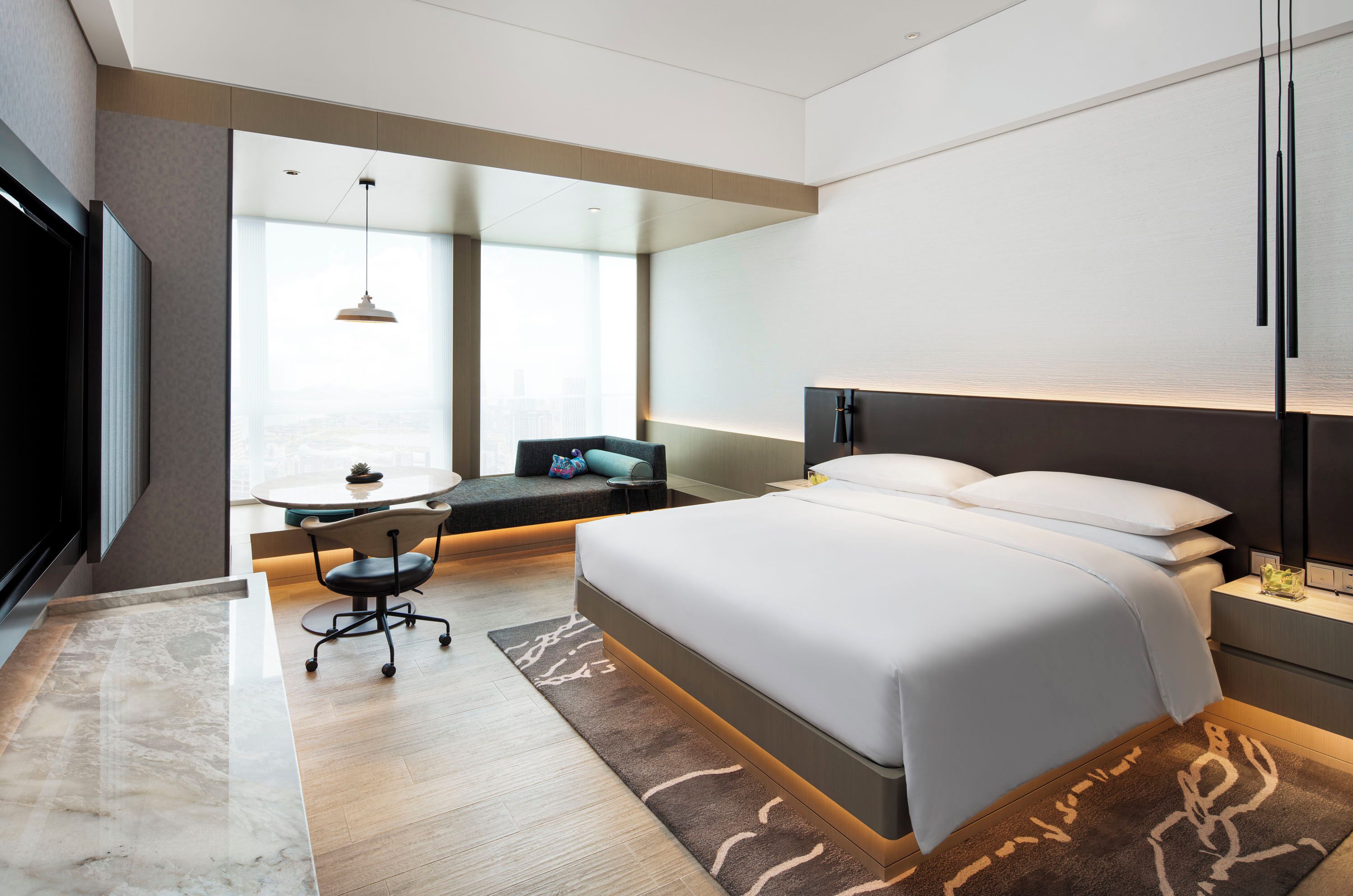 Een moderne hotelkamer met een groot bed, een bureau en uitzicht op de stad.