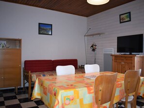 Ett rum med ett matbord, stolar, en tv och en soffa.